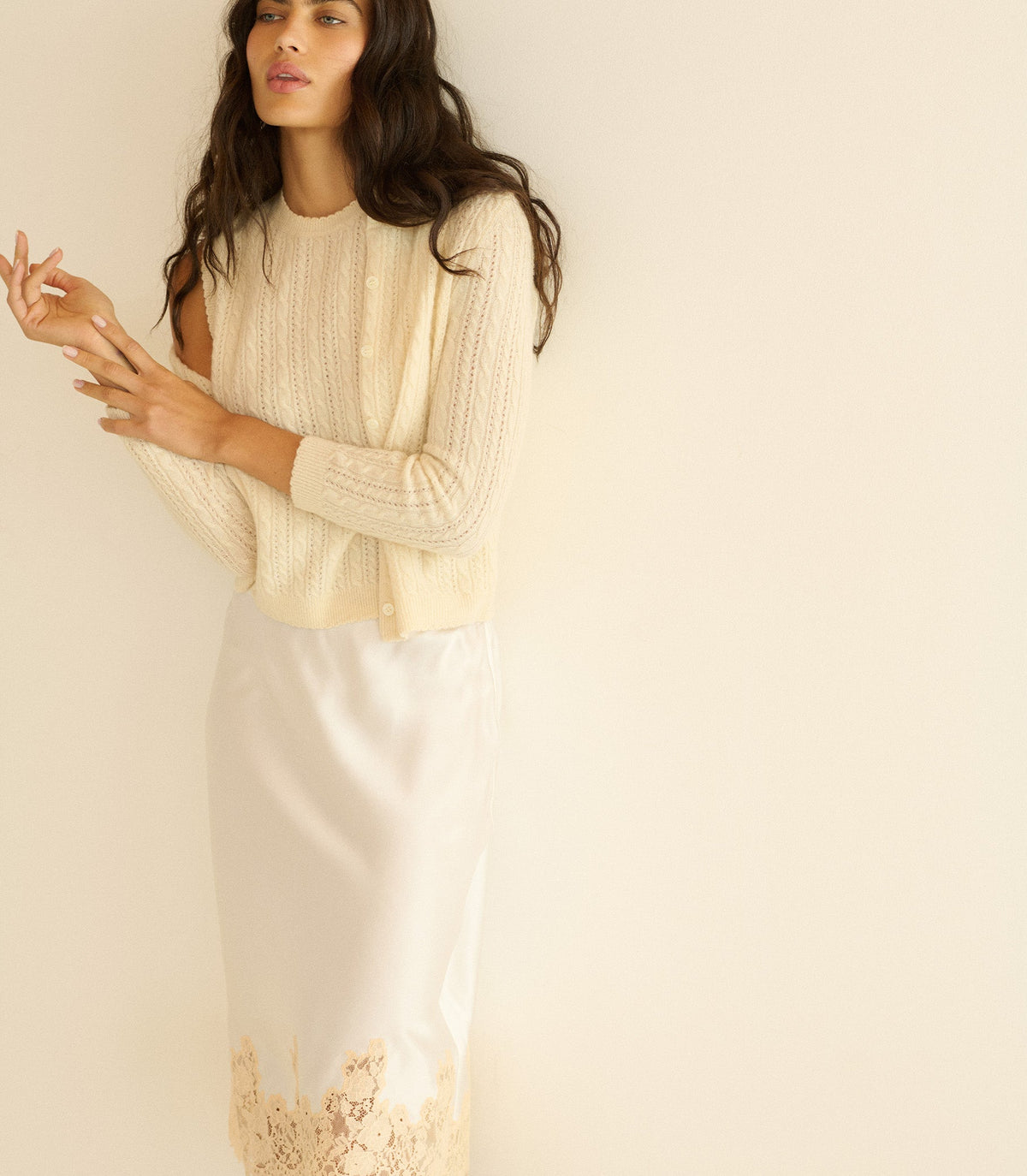 Woman wearing a light-colored top and skirt against a plain background